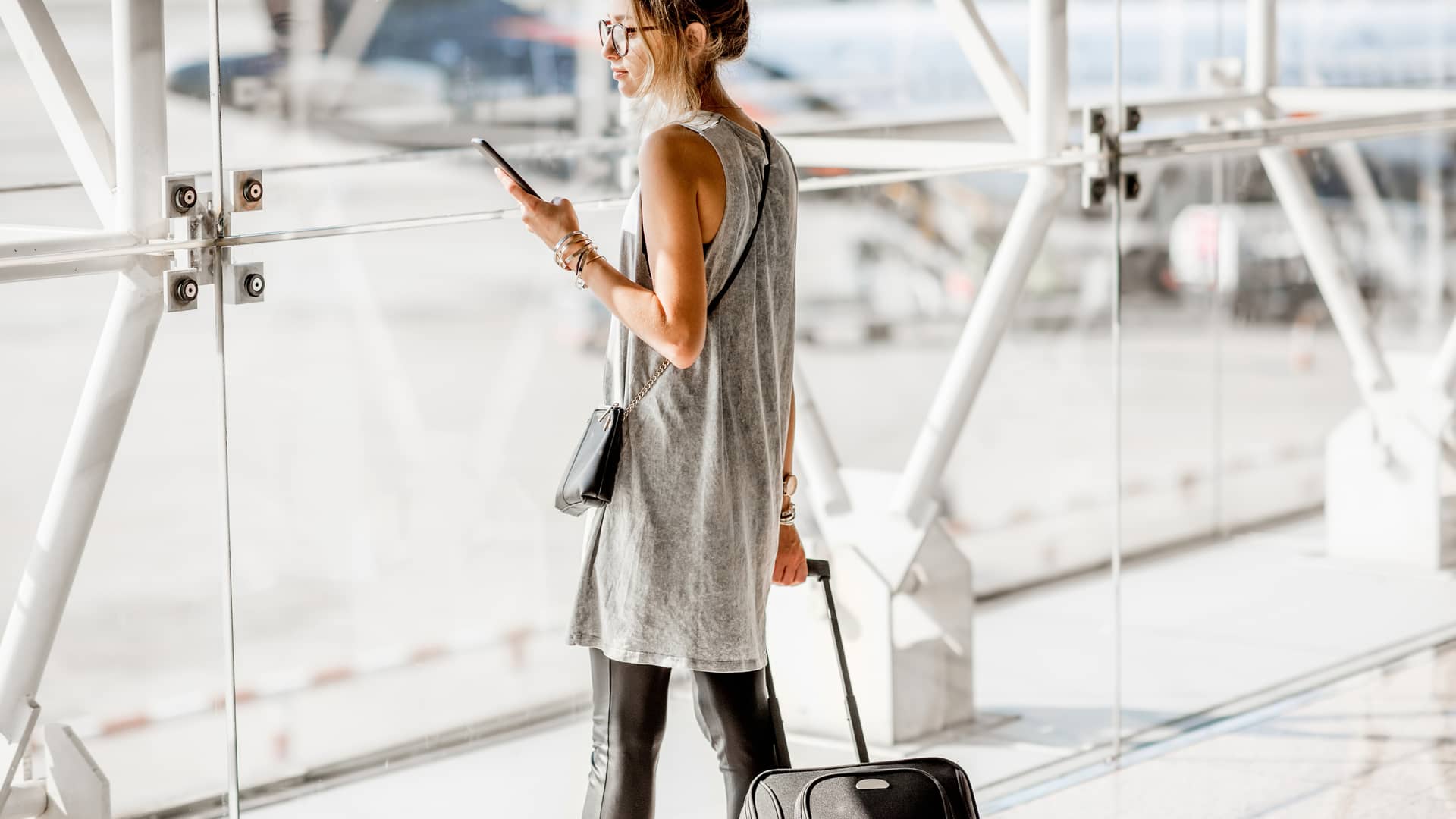 Mujer de negocios viendo su smartphone en el aeropuerto representa datos ilimitados masmovil