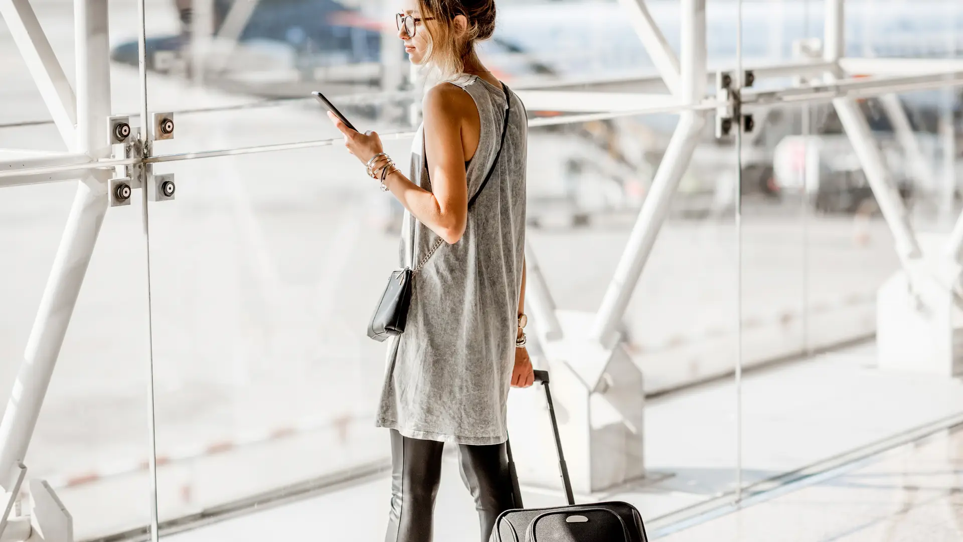 Mujer de negocios viendo su smartphone en el aeropuerto representa datos ilimitados masmovil Mujer de negocios viendo su smartphone en el aeropuerto representa datos ilimitados masmovil