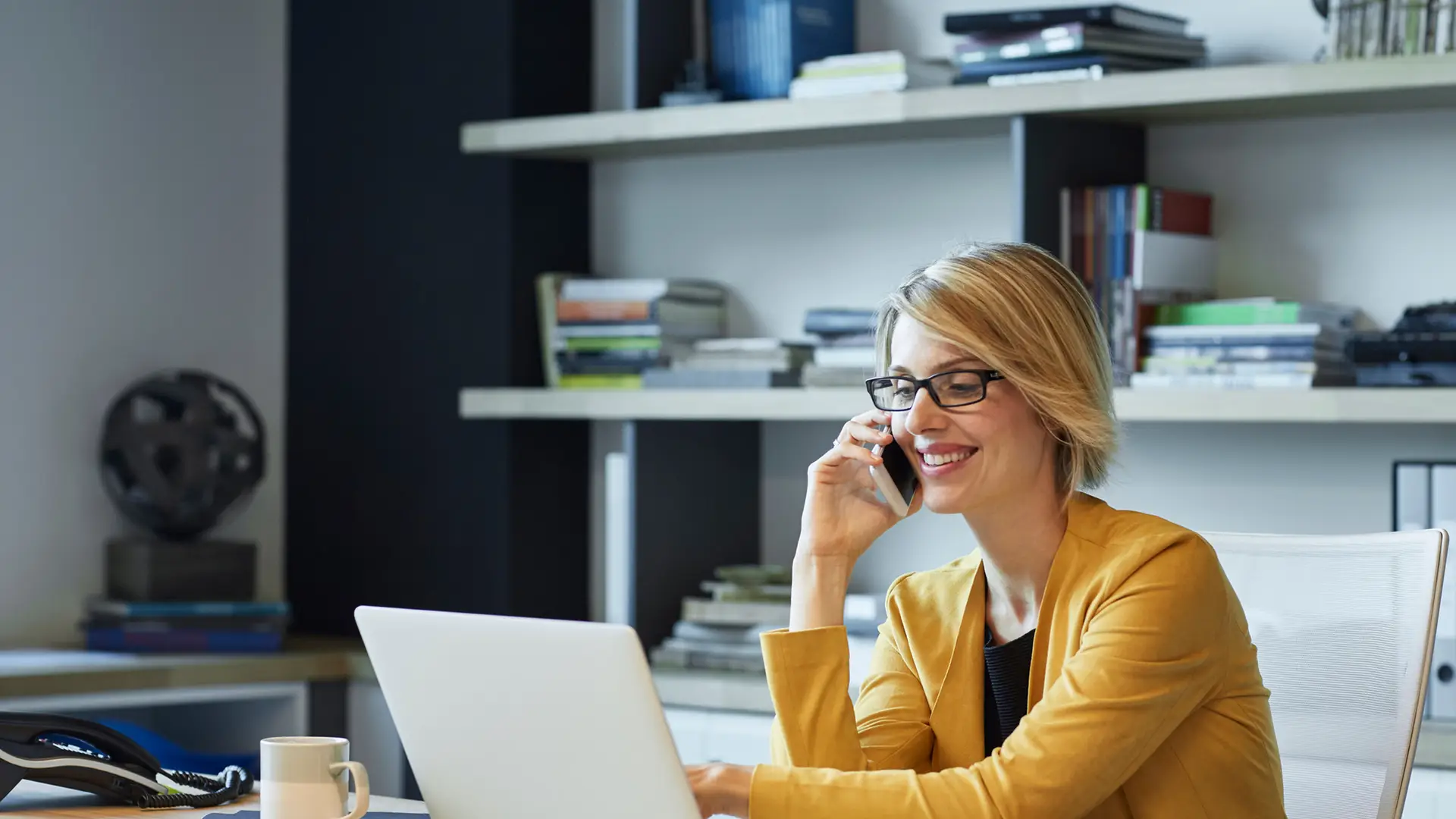 Mujer de negocios con ordenador portátil y teléfono solicitando desactivar el buzón de voz de másmovil Mujer de negocios con ordenador portátil y teléfono solicitando desactivar el buzón de voz de másmovil