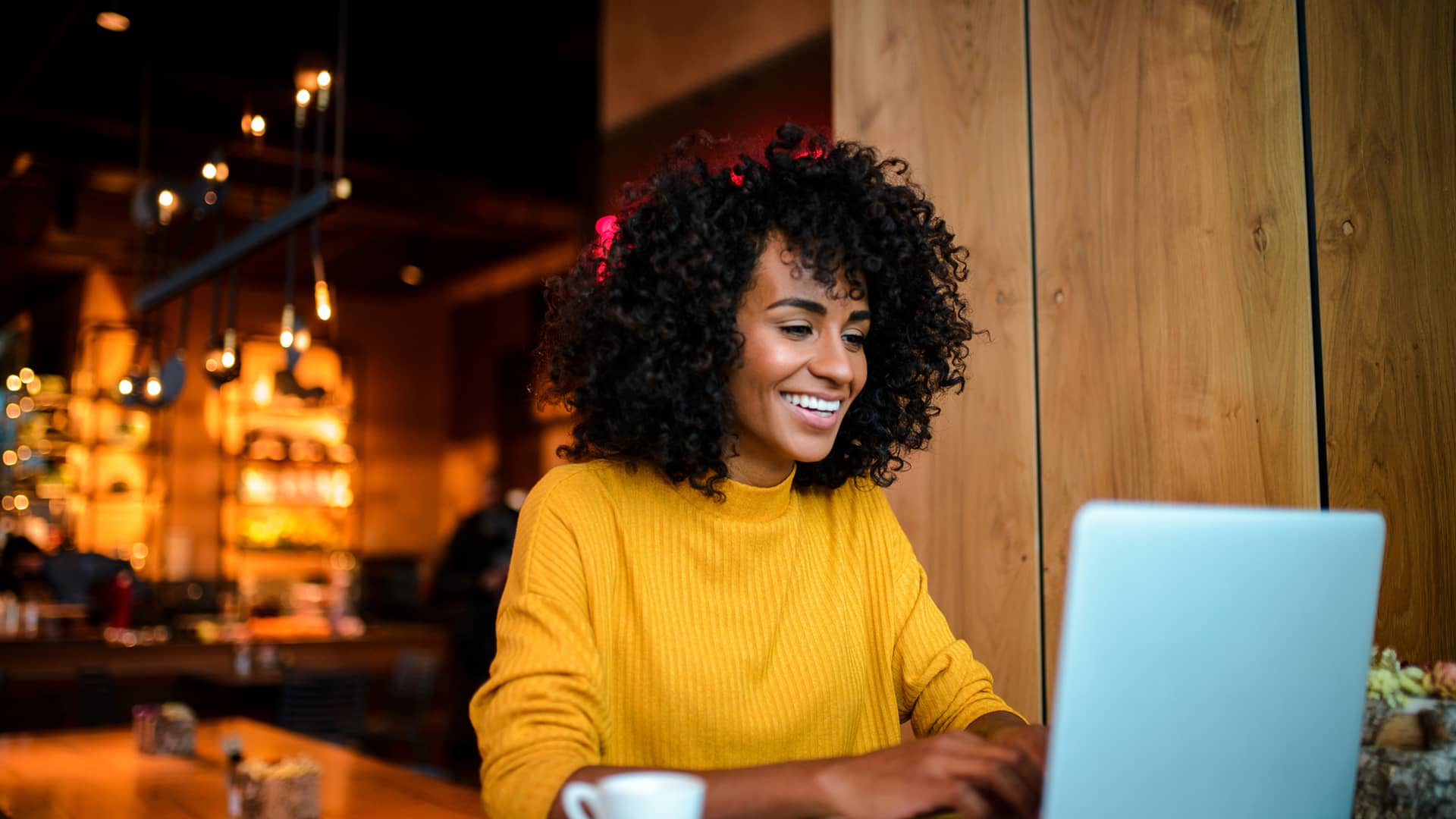 Mujer sonriente usando Laptop en el bar simboliza tarifas internet másmovil