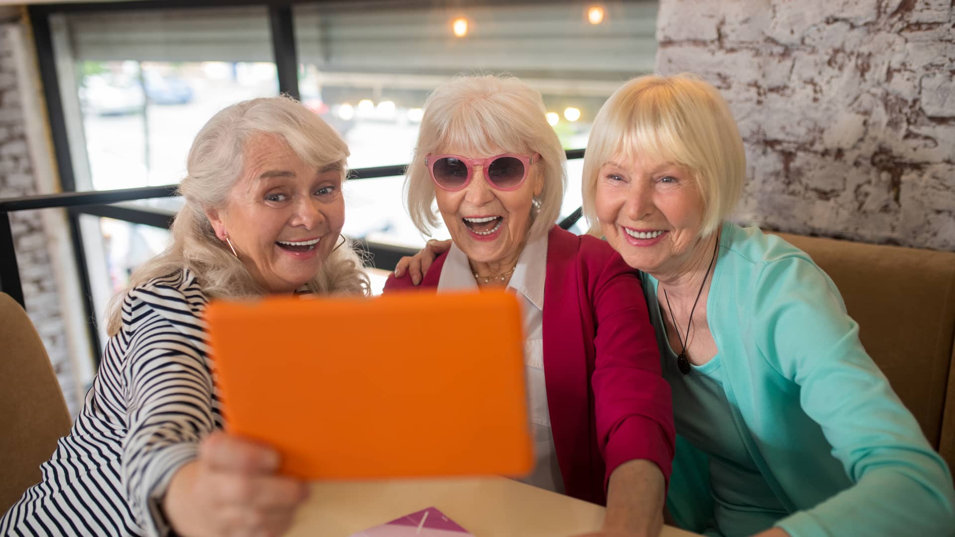 Tres mujeres mayores sonrientes durante una videollamada con otra amiga aprovechando su tarifa móvil movilfly