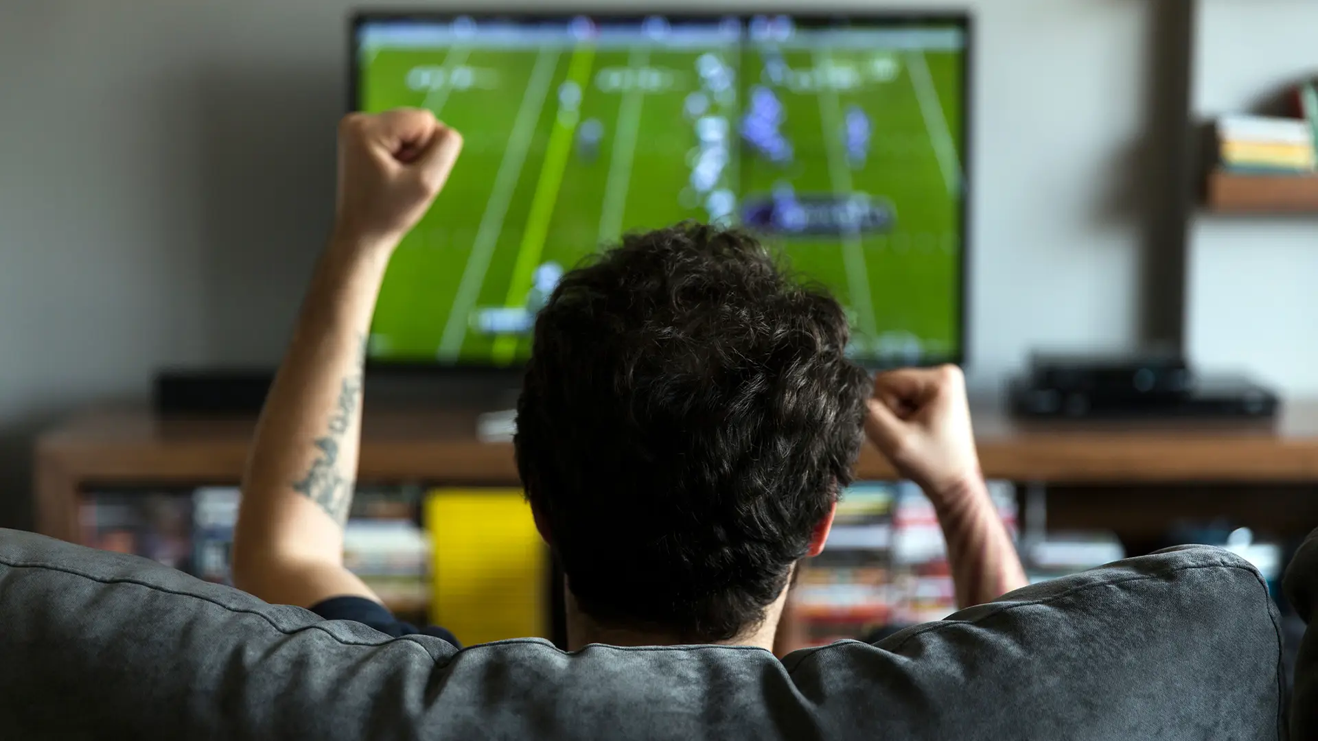 Joven viendo partido de fútbol alegre porque ha logrado cambiar contraseña movistar plus Joven viendo partido de fútbol alegre porque ha logrado cambiar contraseña movistar plus