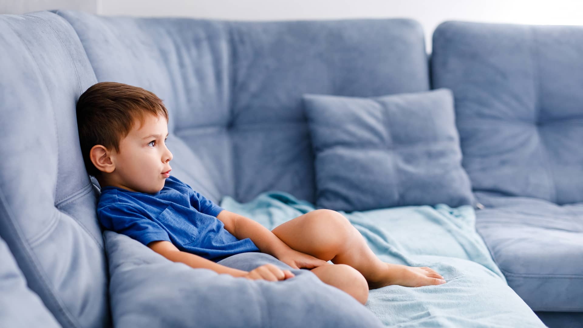 Niño en sofá azul disfruta de los canales de televisión infantil que ofrece Movistar