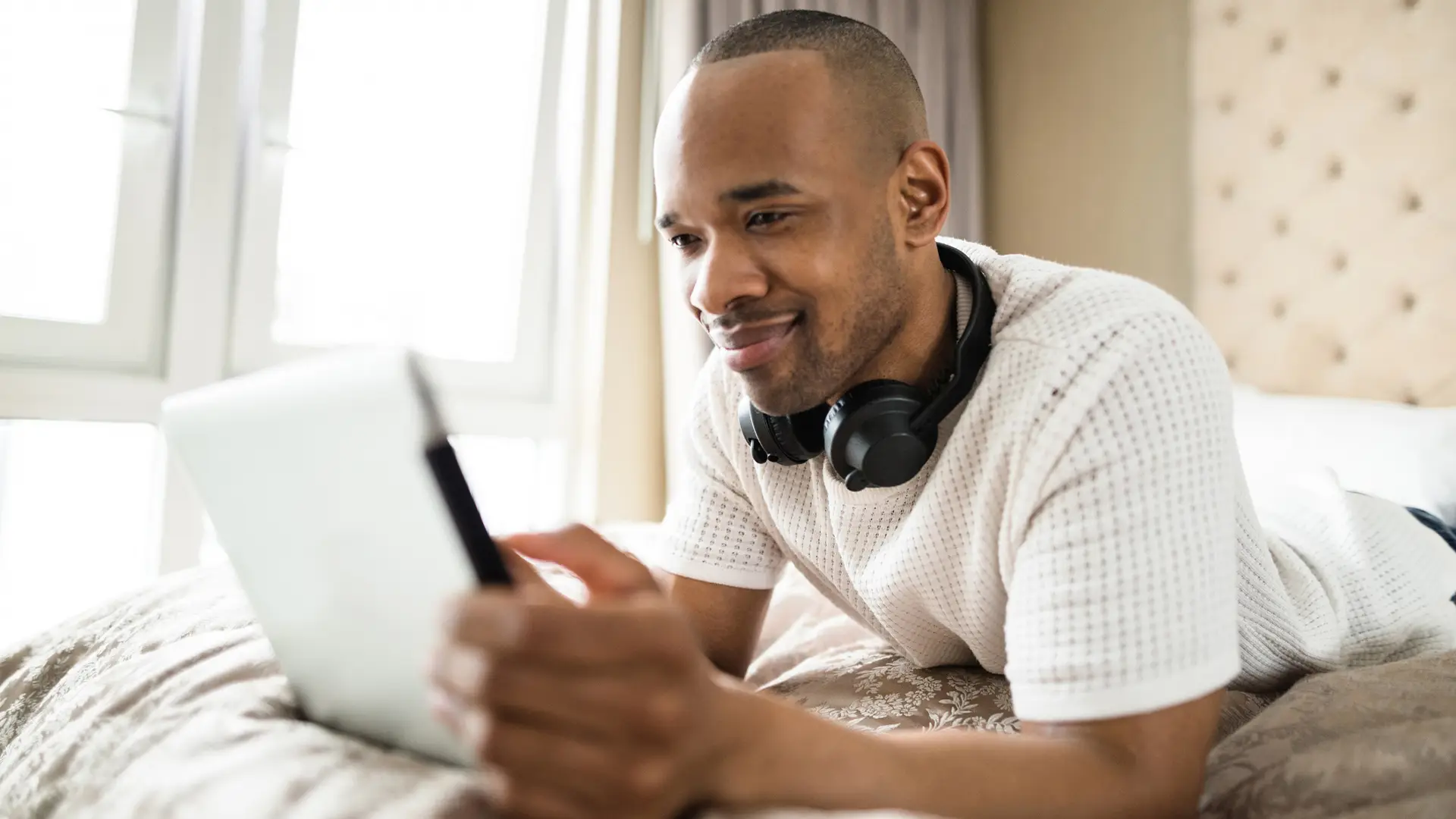 Hombre tumbado en la cama viendo pluto tv en su tablet