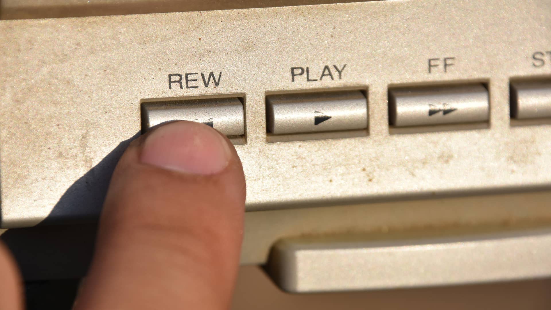 Joven pulsando el botón de rebobinar simboliza rebobina televisión