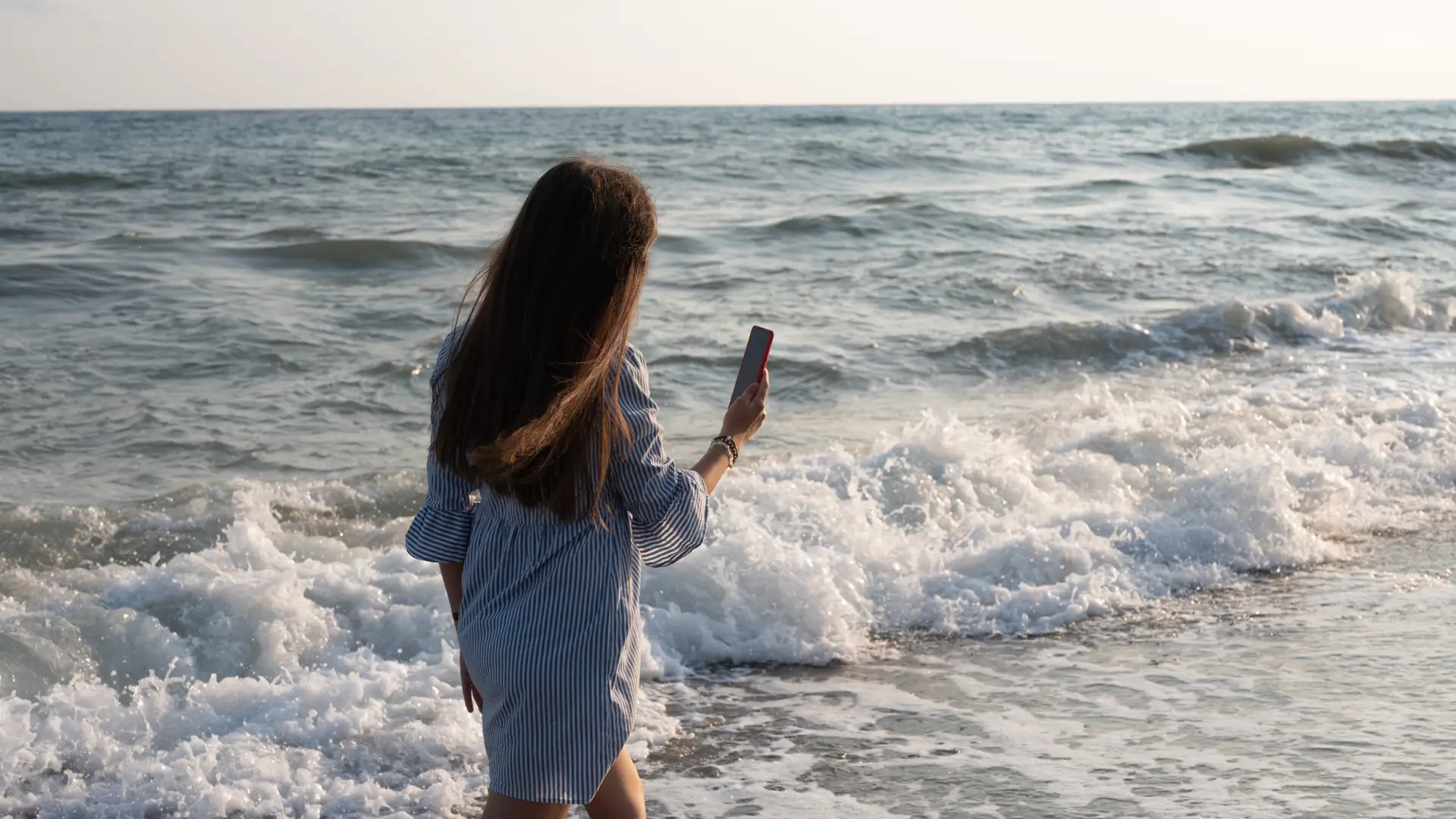 Joven camina por la playa mientras realiza una videollamada gracias al servicio de desvio de llamadas de o2 Joven camina por la playa mientras realiza una videollamada gracias al servicio de desvio de llamadas de o2