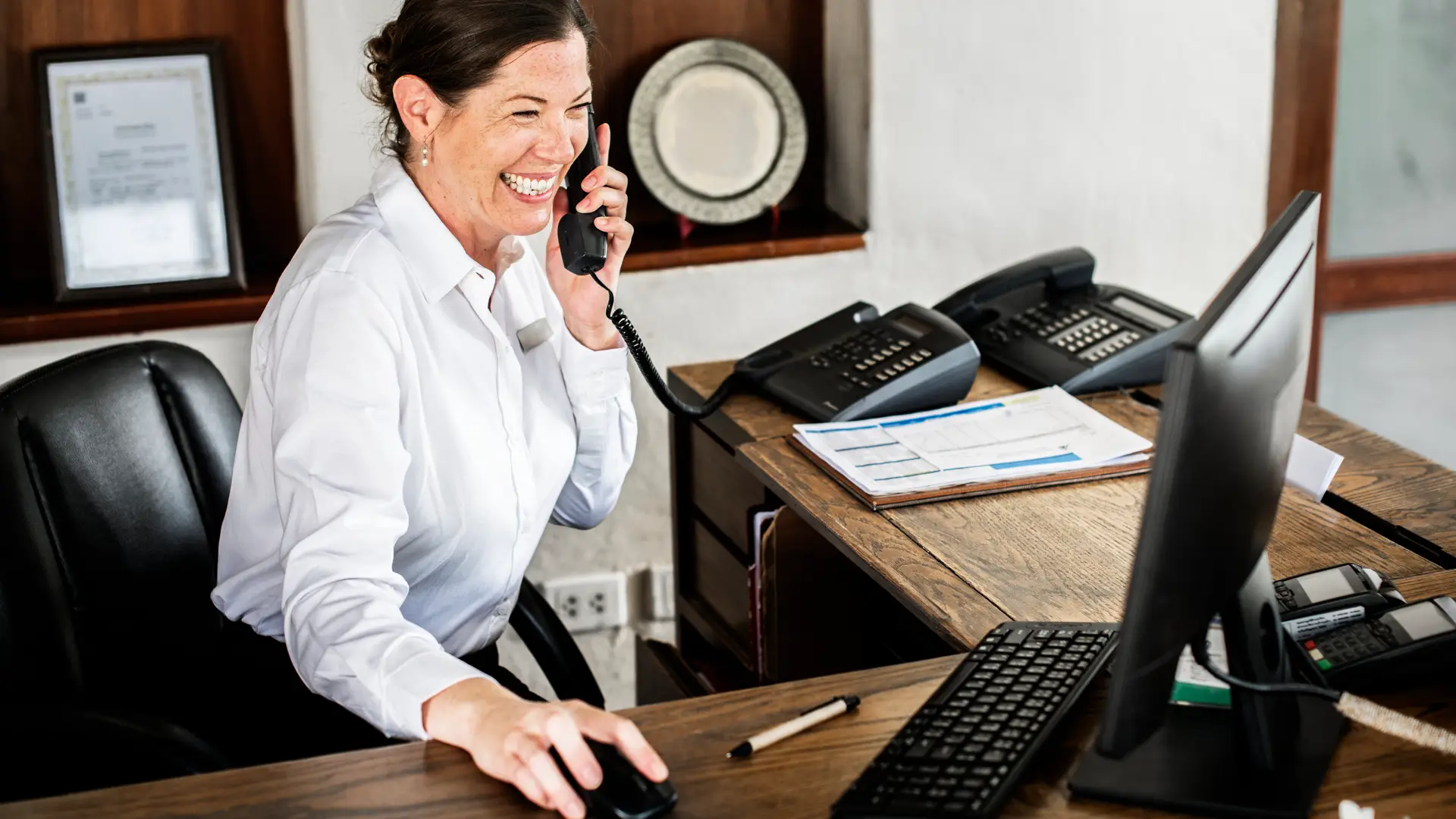 Recepcionista sonrie al teléfono pues pudo personalizar su saludo al contar con el identificador de llamadas de O2