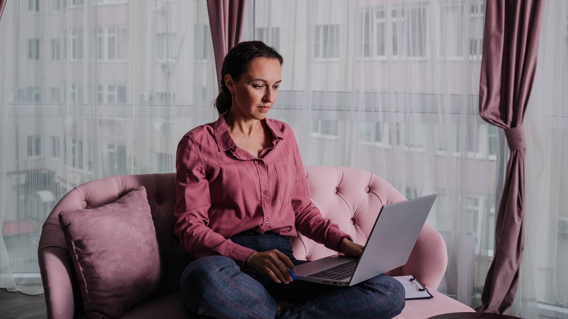 Mujer con camisa rosa navega por internet en su portatil gracias a su tarifa de oceans