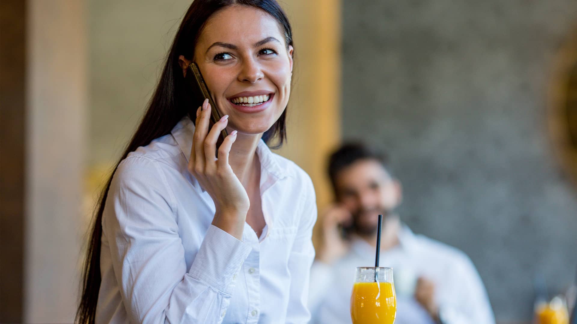 Mujer hablando por teléfono mientras bebe un zumo para contenta por estar cancelando su portabilidad