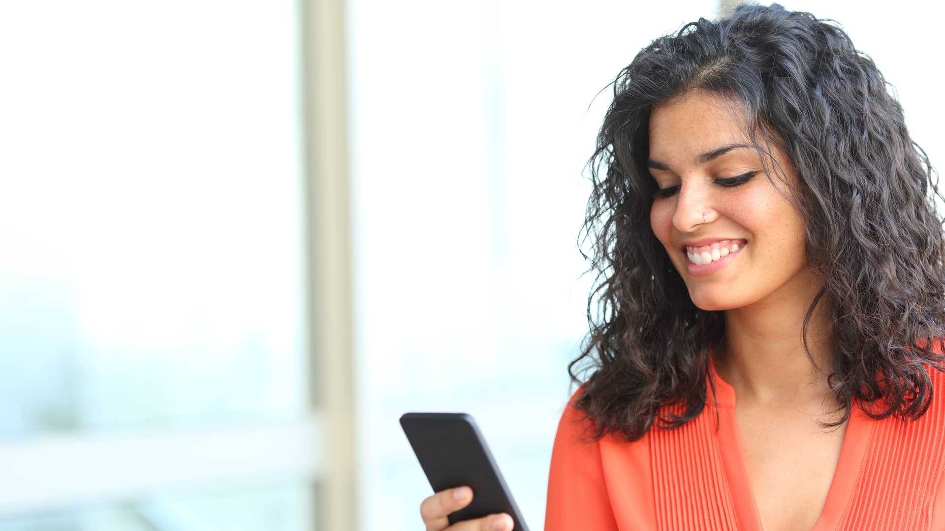 Mujer sonriente usando su smartphone viendo ofertas de orange
