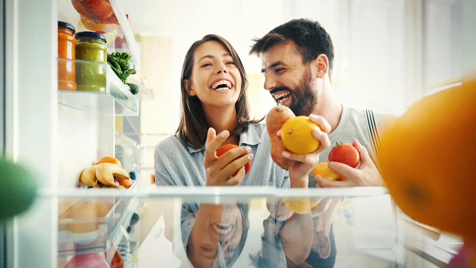 Recien casados abriendo la puerta de la nevera representan permanencia de orange