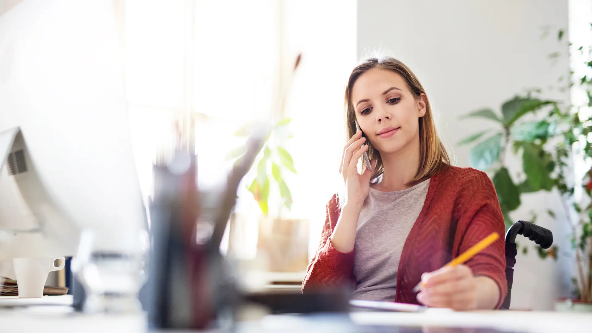 Mujer en su trabajo atendiendo llamada desviada de su teléfono fijo hacia su móvil Mujer en su trabajo atendiendo llamada desviada de su teléfono fijo hacia su móvil