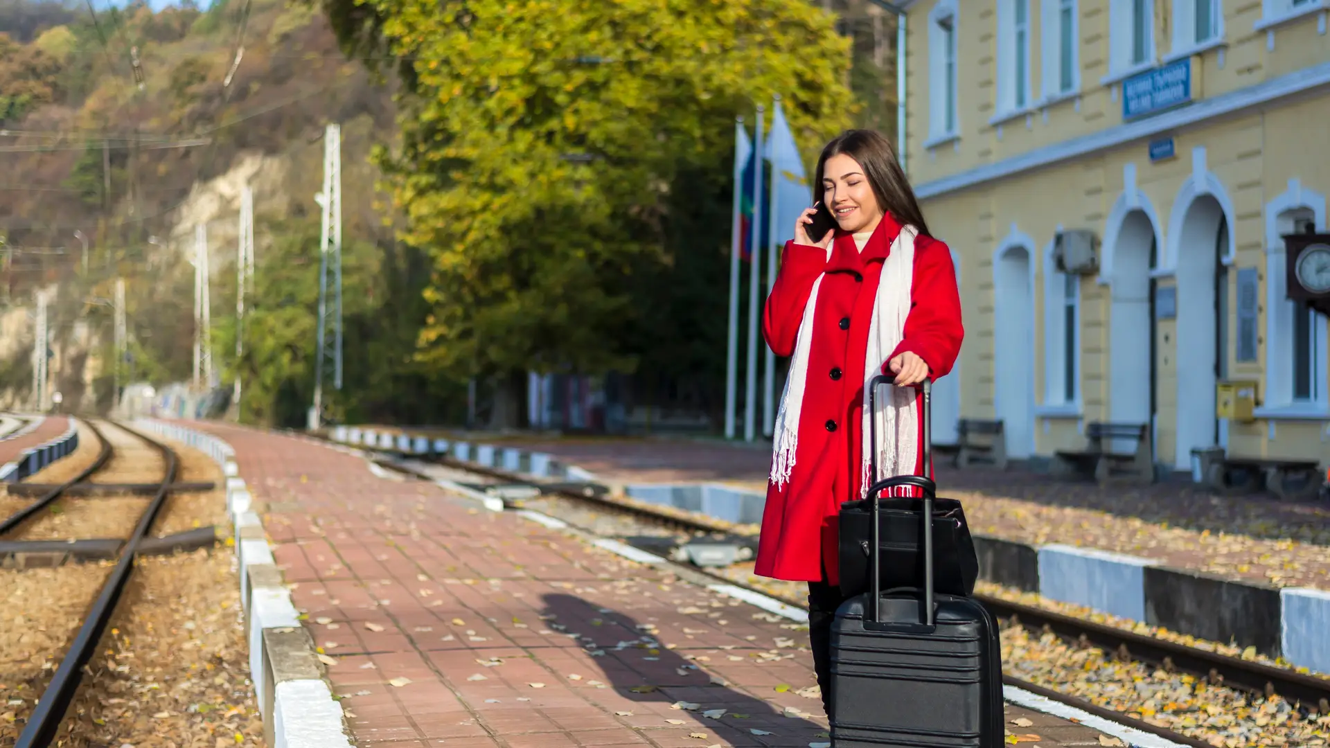 Joven en anden de tren esperando con su maleta mientras habla por teléfono simboliza roaming pepephone Joven en anden de tren esperando con su maleta mientras habla por teléfono simboliza roaming pepephone