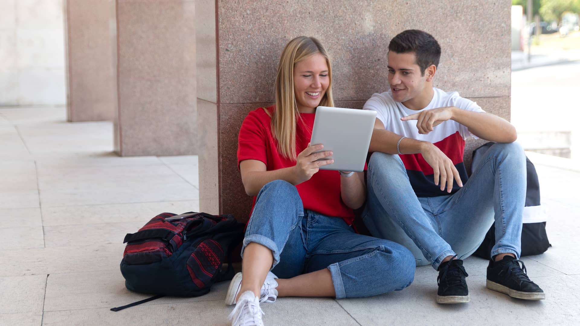 Jovenes usando tablet conectada al internet de su smartphone con el tethering de pepephone