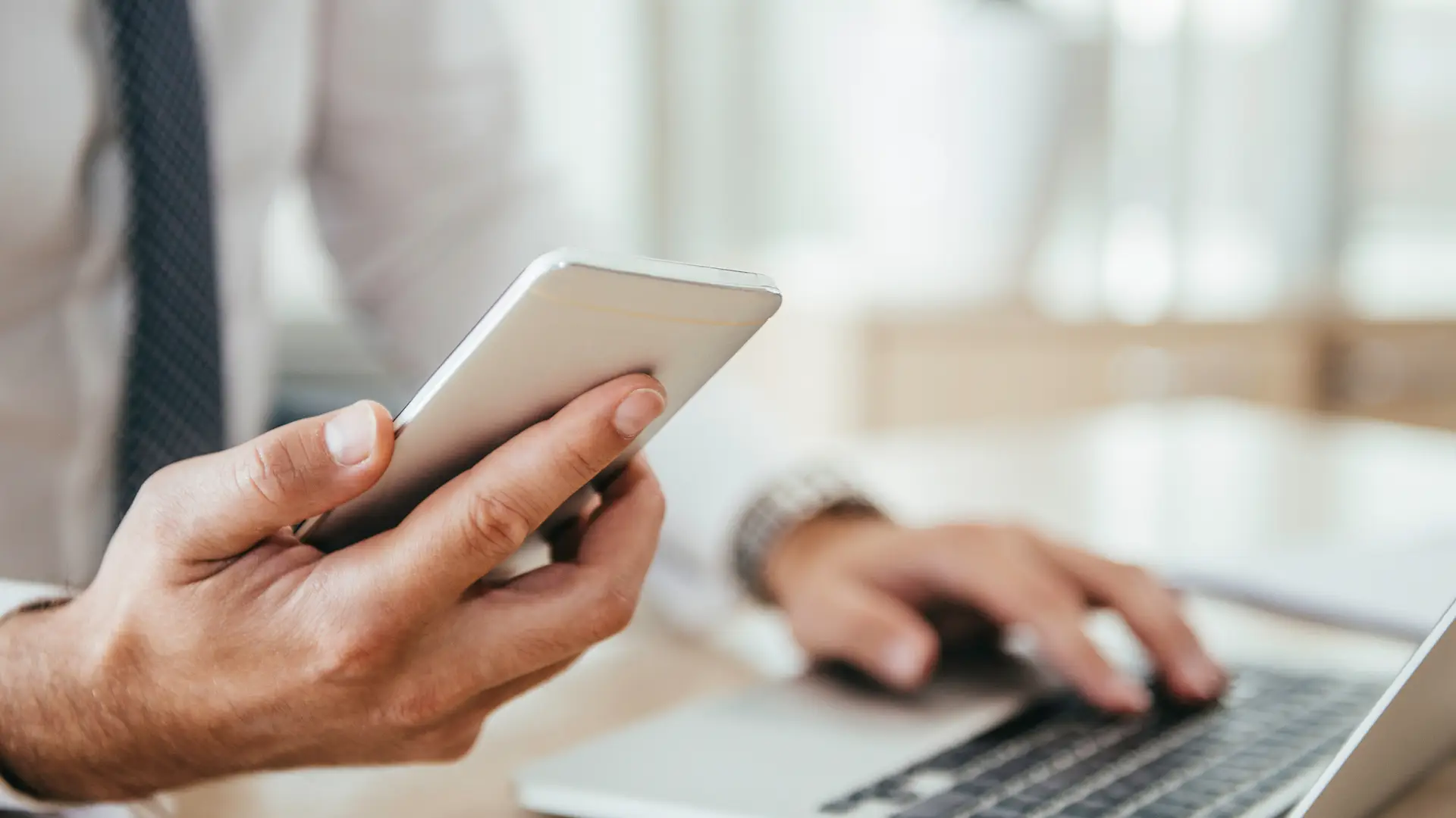 Persona con smartphone usando su portátil simboliza tarifas móvil e internet de pepephone Persona con smartphone usando su portátil simboliza tarifas móvil e internet de pepephone