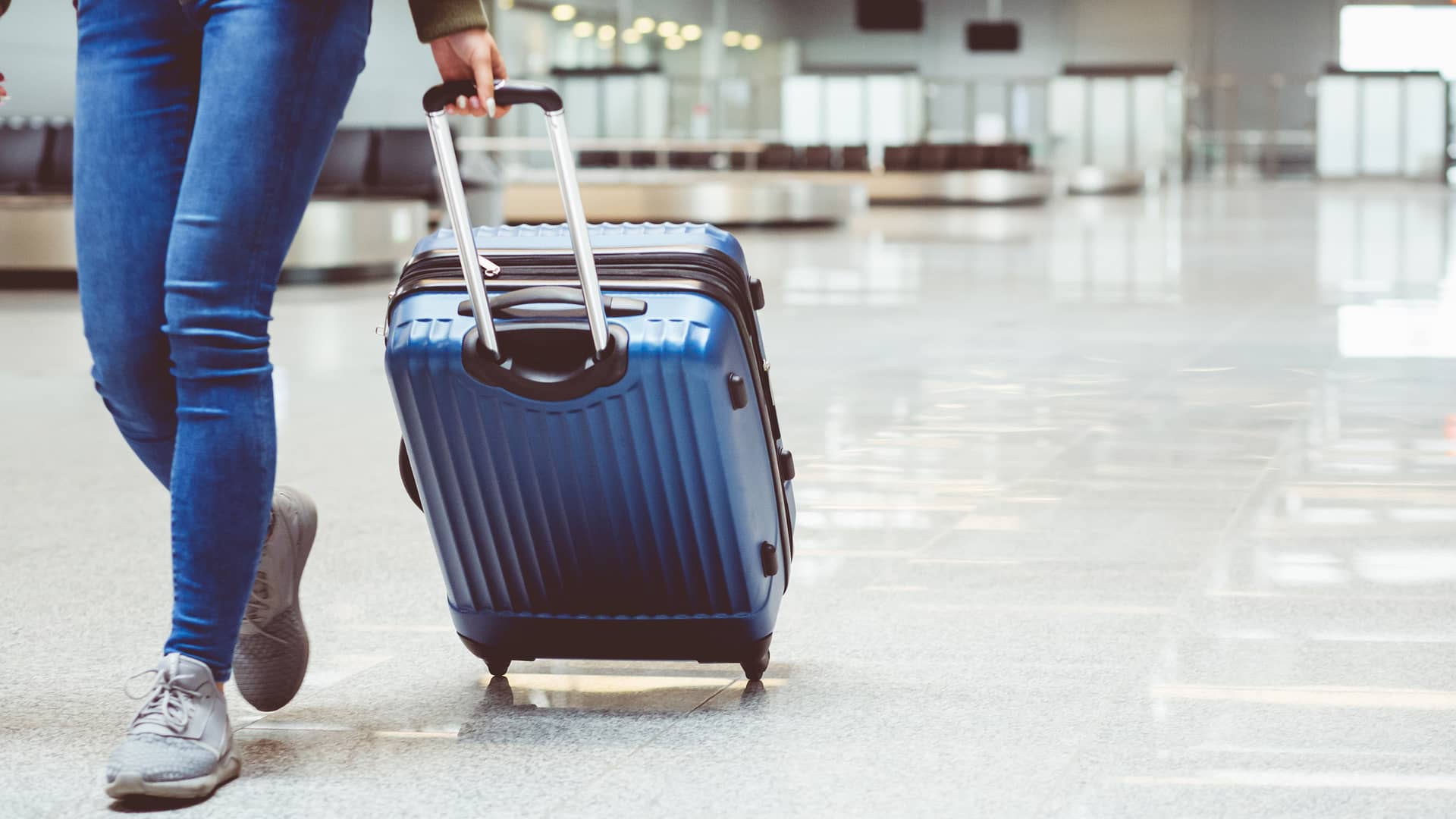 Joven en aeropuerto con maleta representa roaming de república móvil