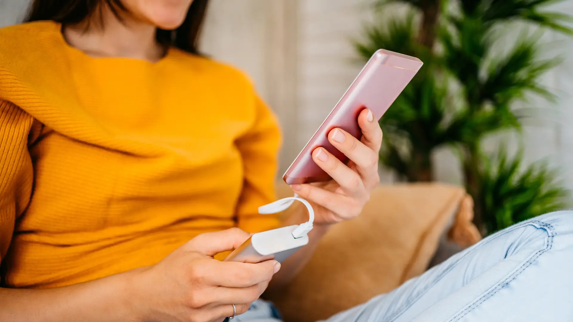 Mujer cargando teléfono con un banco de energía mientras busca como configurar la apn de su teléfono Mujer cargando teléfono con un banco de energía mientras busca como configurar la apn de su teléfono