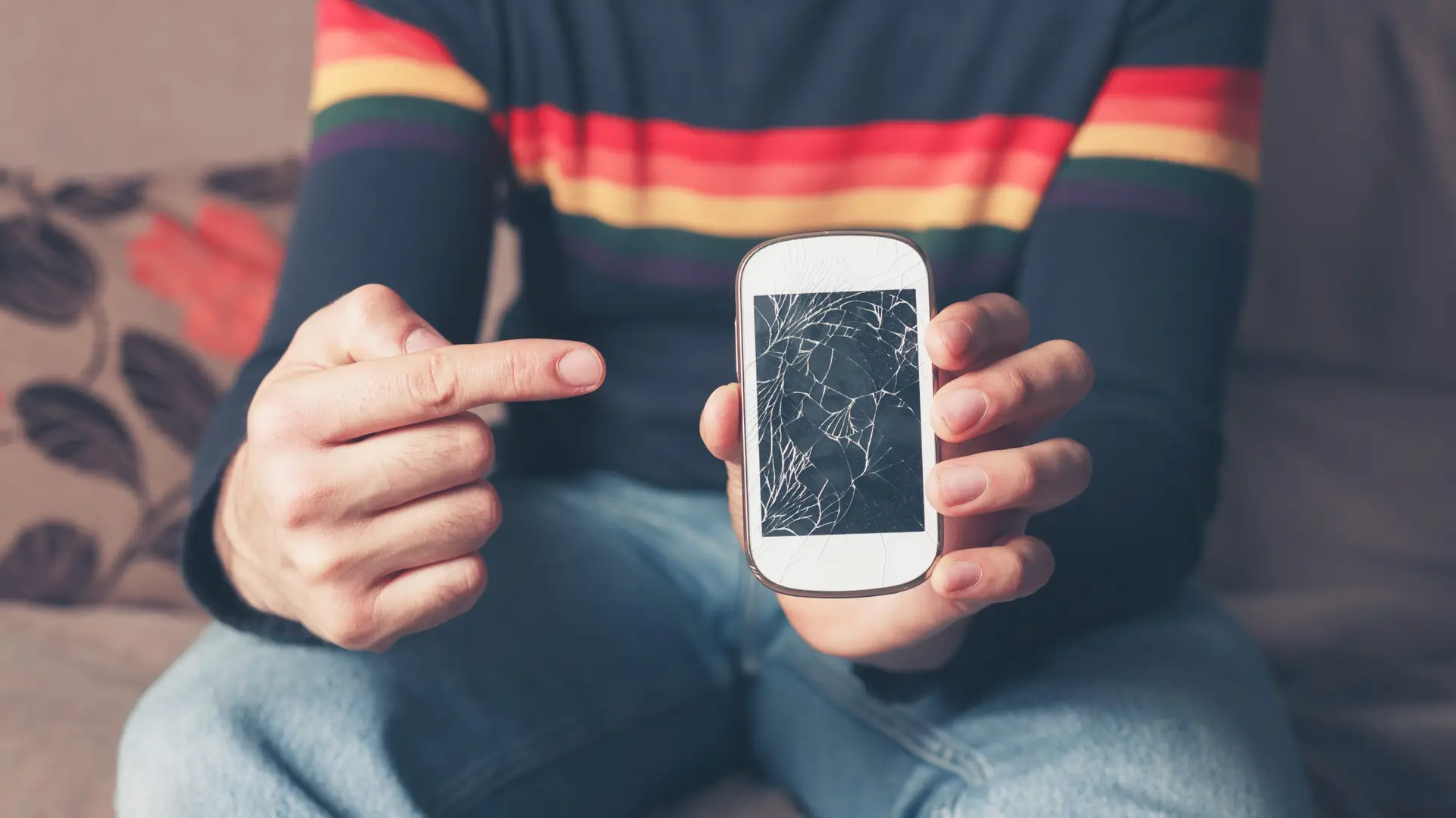chico señalando la pantalla rota de su telefono que no puede arreglar porque no existe seguro movil de simyo chico señalando la pantalla rota de su telefono que no puede arreglar porque no existe seguro movil de simyo