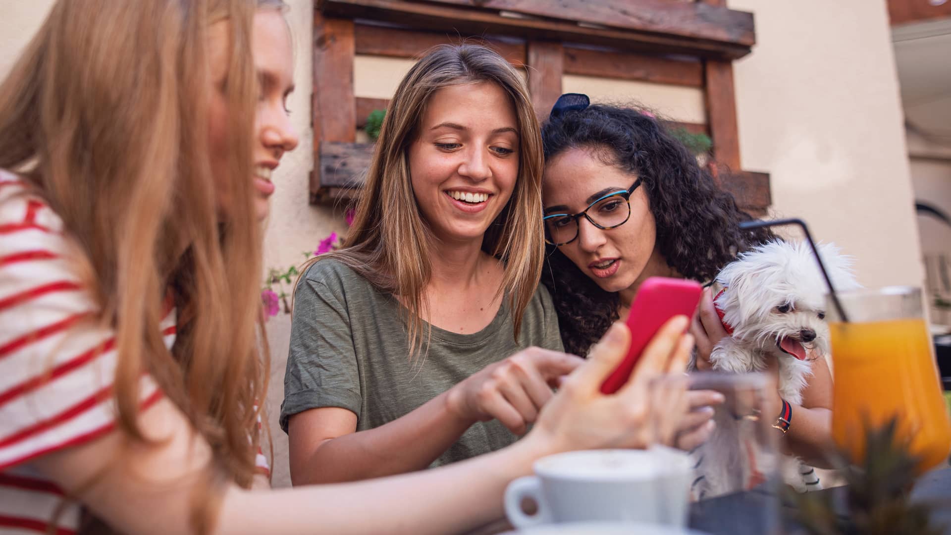 Tres chicas viendo algo en un smartphone representan tarjeta trio de simyo