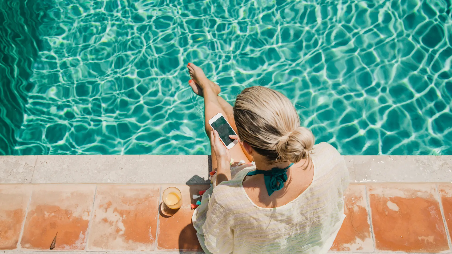 Mujer sentada a pie de piscina usando su smartphone representa movil prepago de suop Mujer sentada a pie de piscina usando su smartphone representa movil prepago de suop