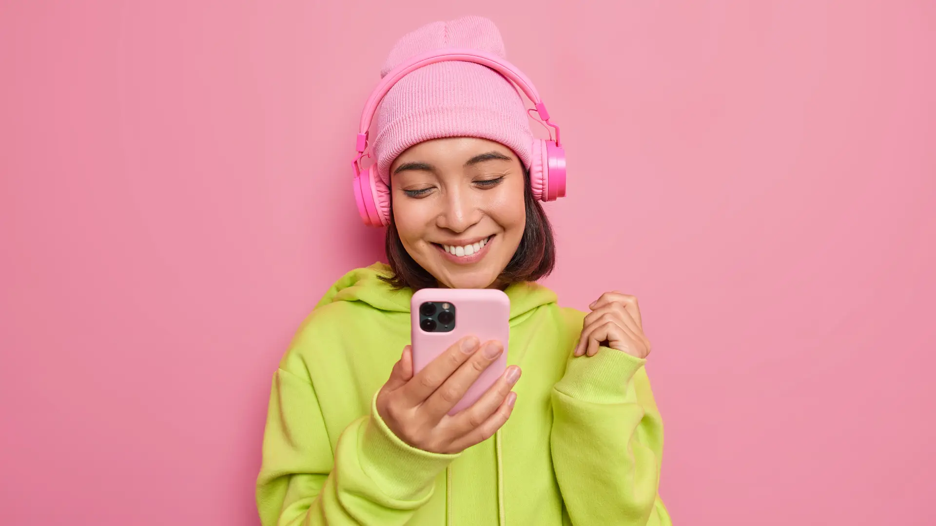 Joven con sudadera verde, consulta en su móvil las nuevas tarifas teléfonicas de sweno Joven con sudadera verde, consulta en su móvil las nuevas tarifas teléfonicas de sweno