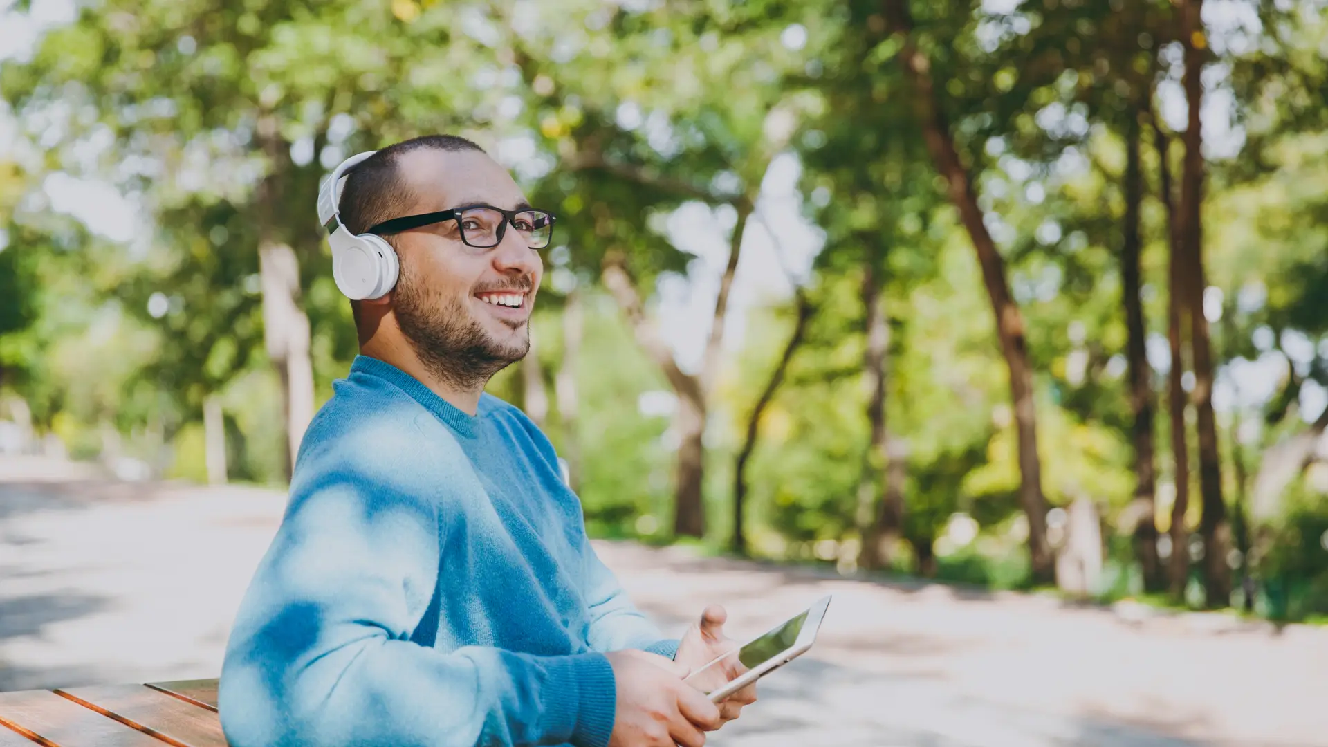 Hombre sentado en un banco, alegre tras consultar en su ipad las nuevas tarifas de sweno Hombre sentado en un banco, alegre tras consultar en su ipad las nuevas tarifas de sweno