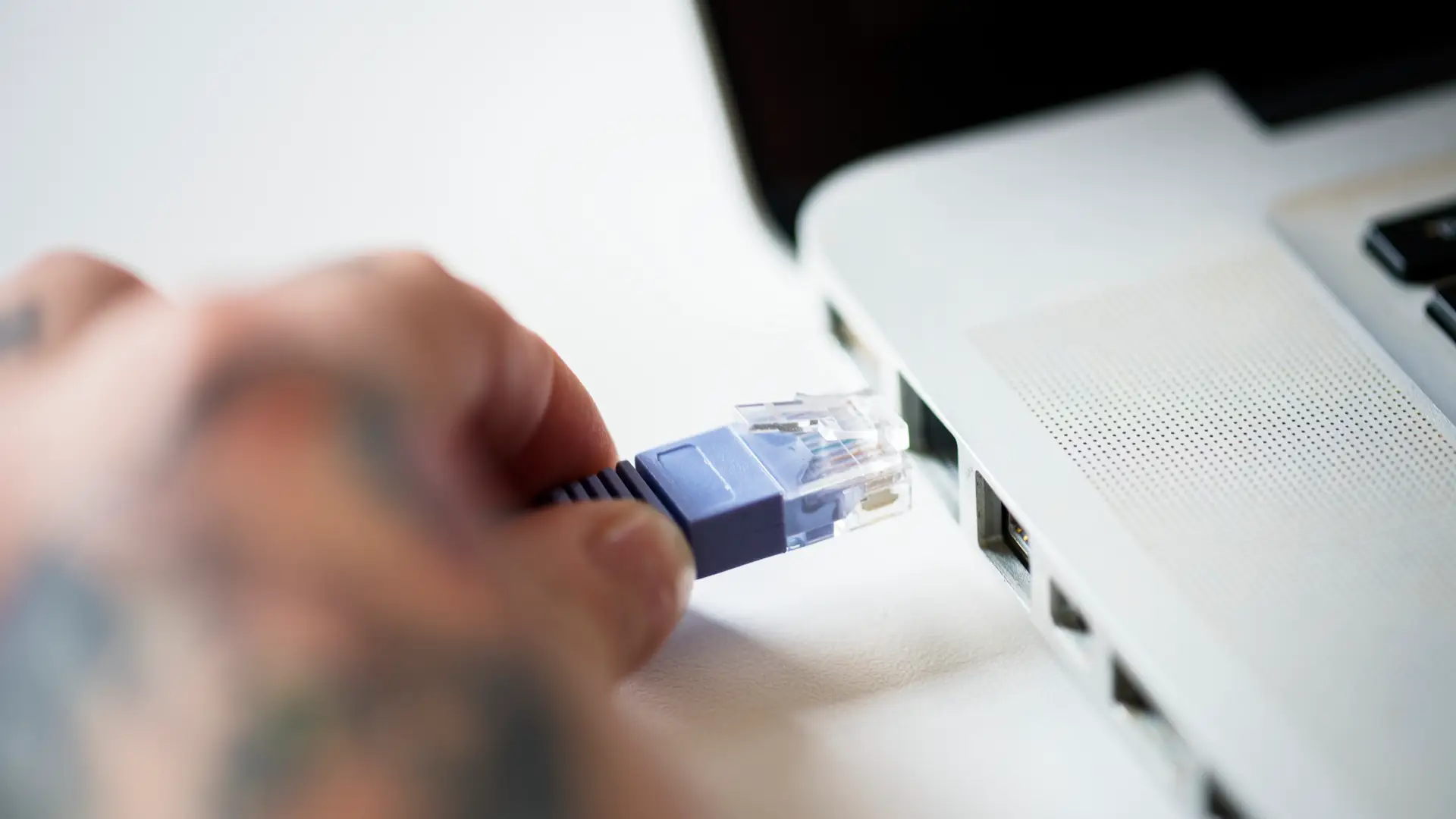 Una persona conectando un cable ethernet al ordenador para cambiar la contraseña de si fibra de wifi