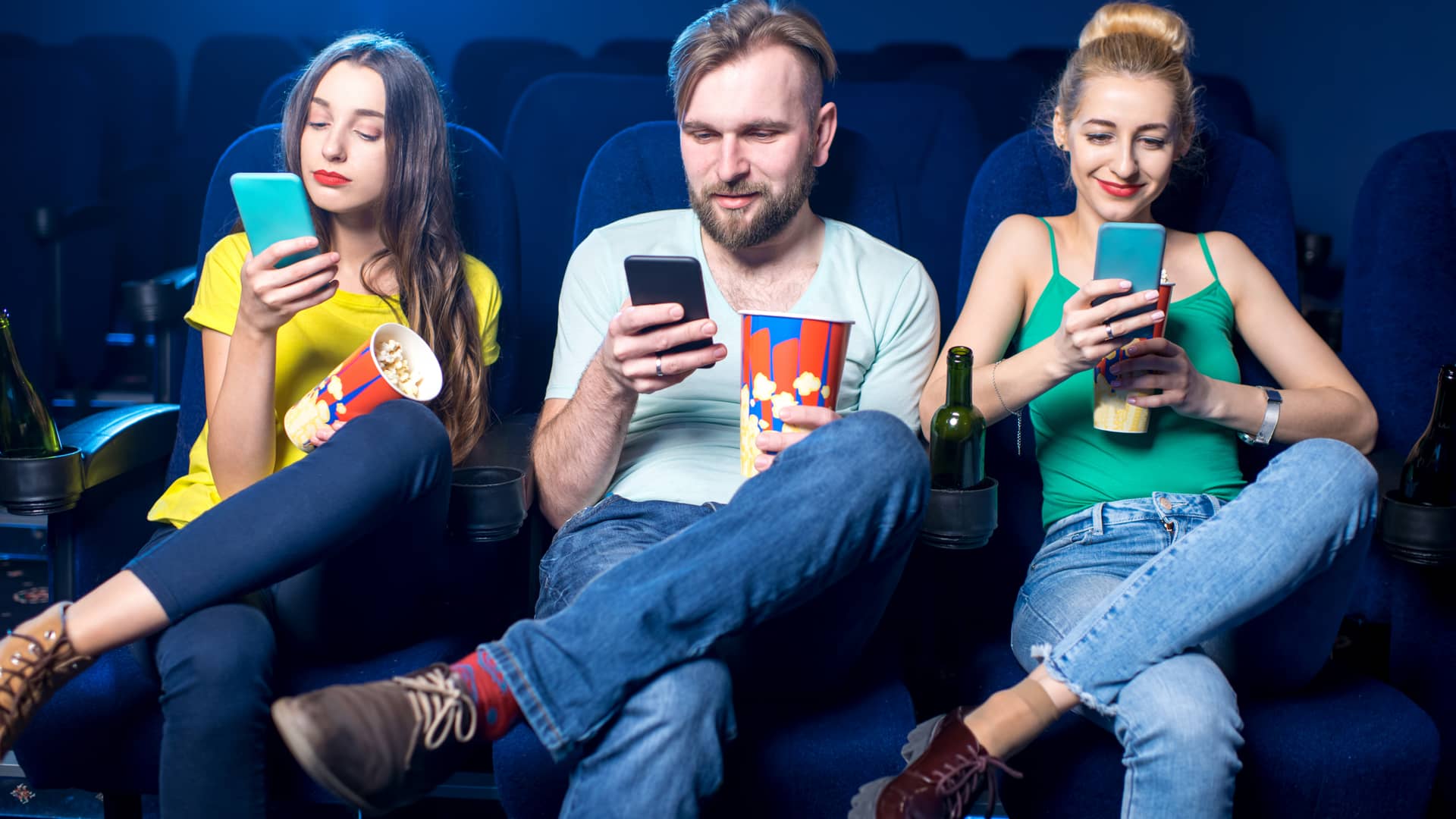 Tres amigos en el cine usando el móvil gracias a que uno de ellos ha compartido datos móviles gracias a su tarifa de Telecable