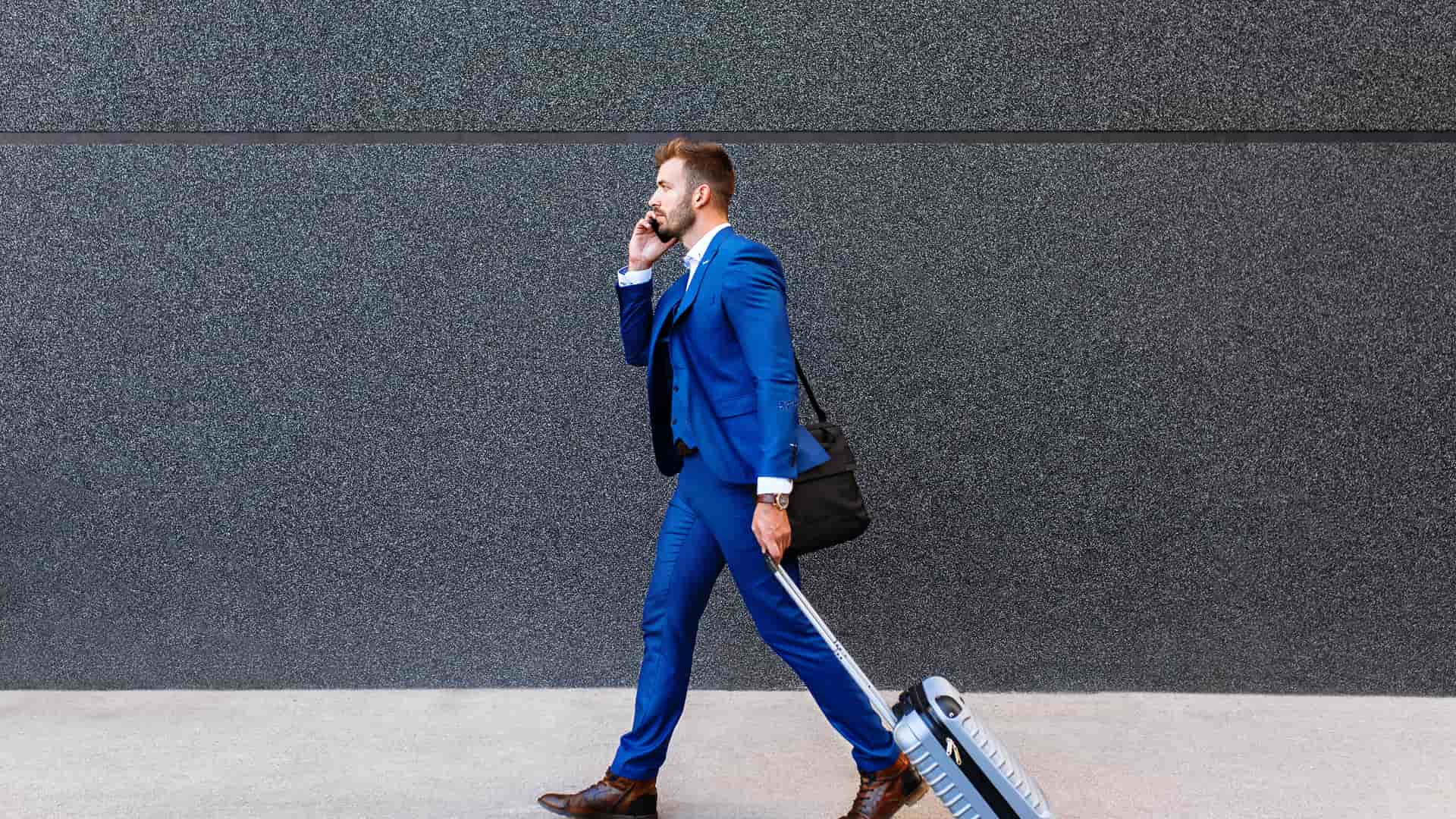 Joven hombre de negocios con maleta y hablando por teléfono representa roaming de telecable