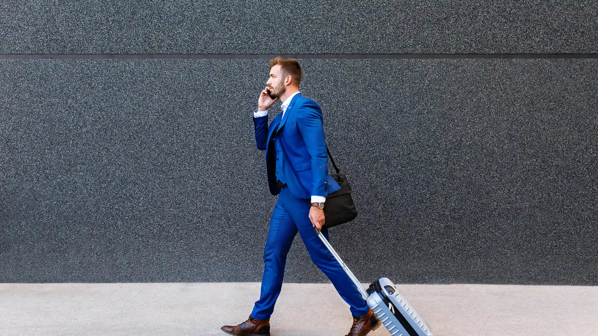 Joven hombre de negocios con maleta y hablando por teléfono representa roaming de telecable Joven hombre de negocios con maleta y hablando por teléfono representa roaming de telecable
