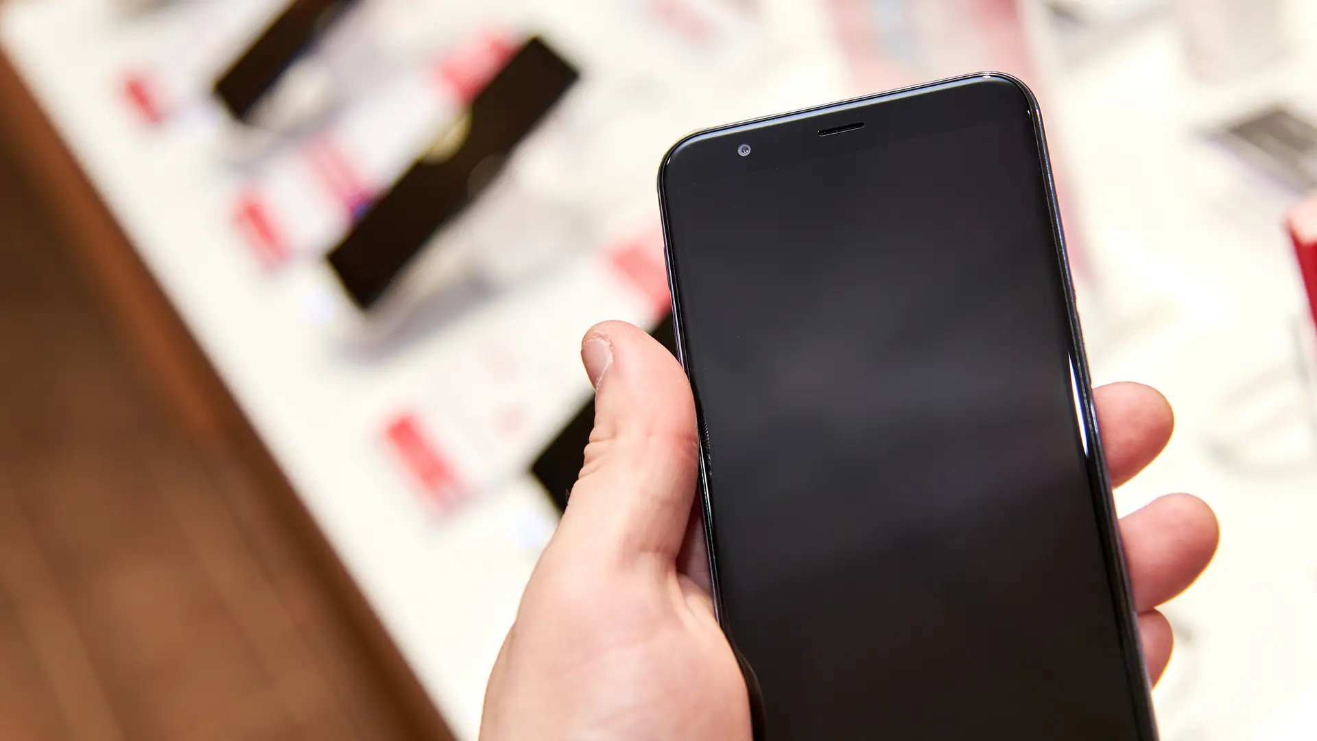 Persona sosteniendo movil de muestra en tienda de telecable