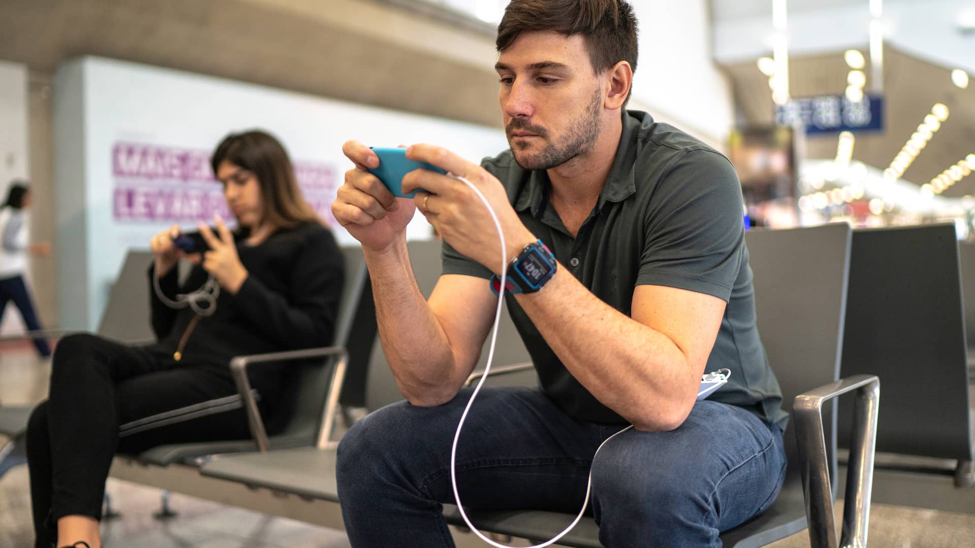 Hombre usando y cargando teléfono en el aeropuerto representa movil prepago recarga