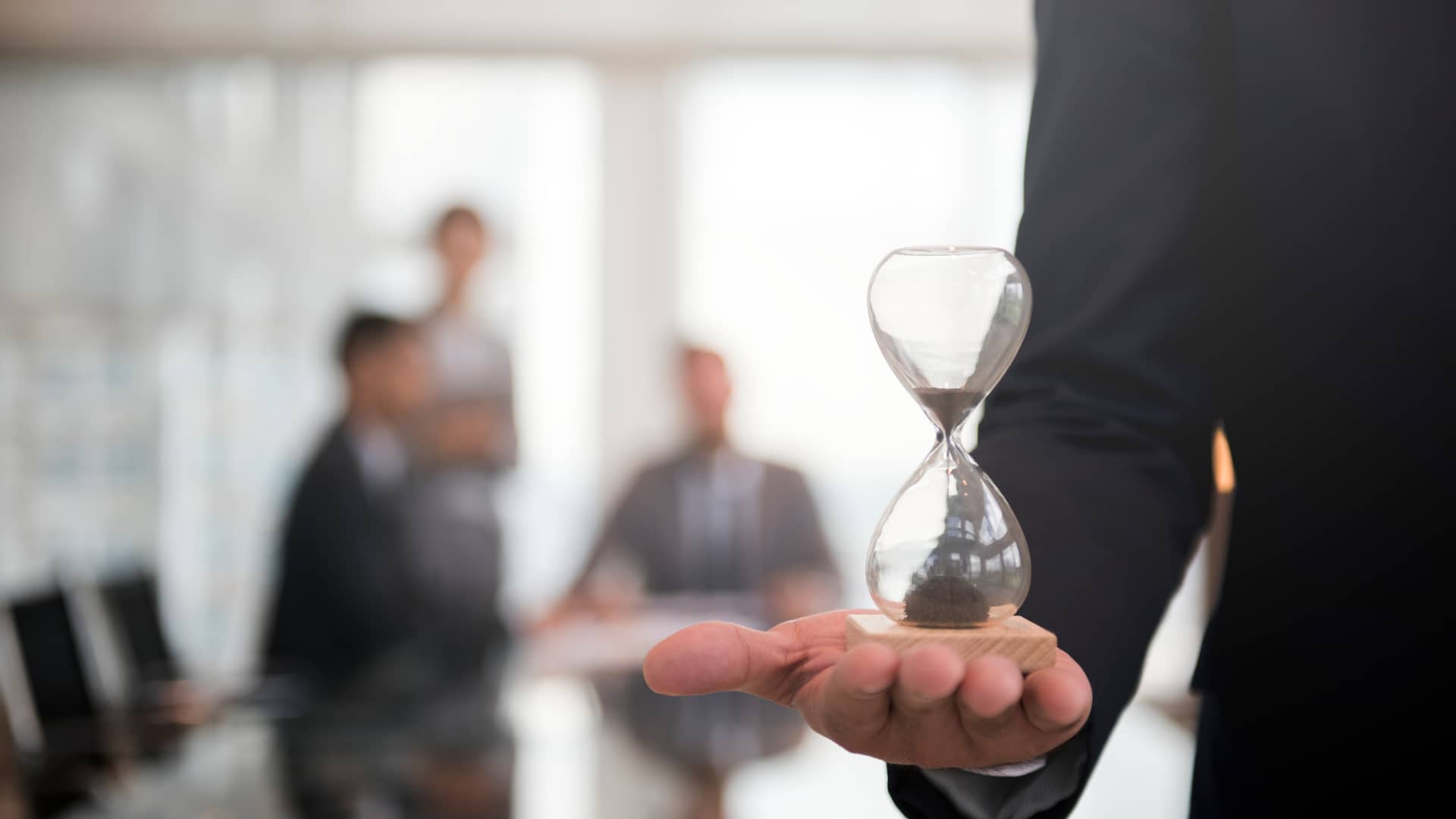 Empresario sostiene un reloj de arena en su mano, representando la app de control de horarios para empresas sesame time