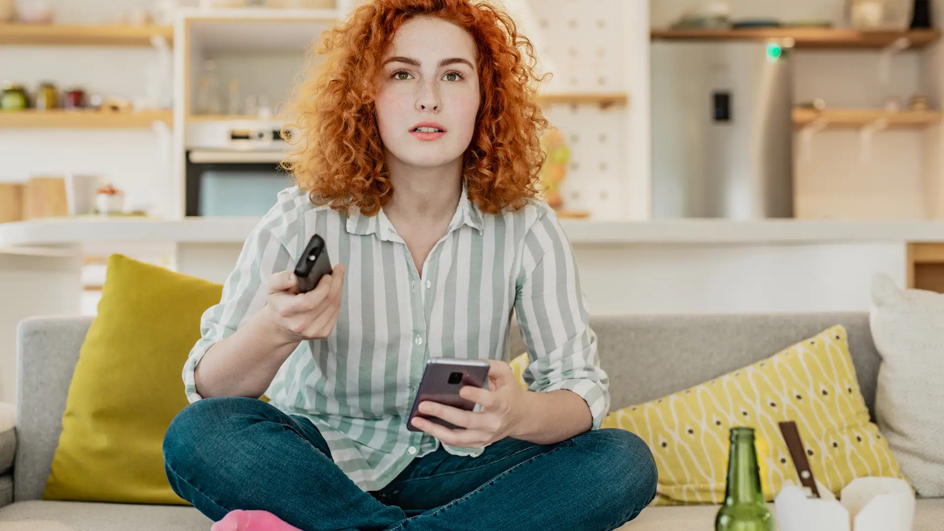 Joven con móvil atenta viendo series gracias a vodafone televisión incluido en su tarifa