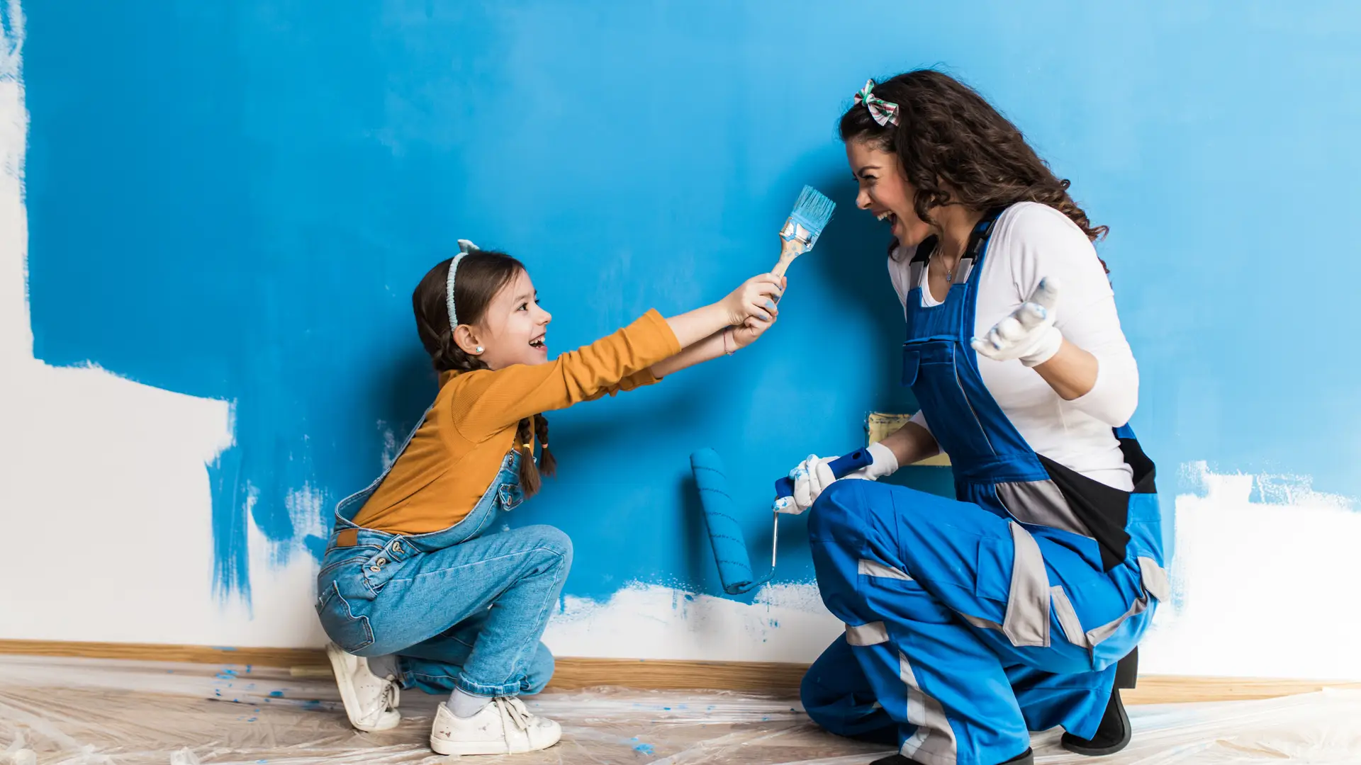 Una chica pintando la pared de color azul con su hija que representa la portabilidad de la compañía Xenet Una chica pintando la pared de color azul con su hija que representa la portabilidad de la compañía Xenet