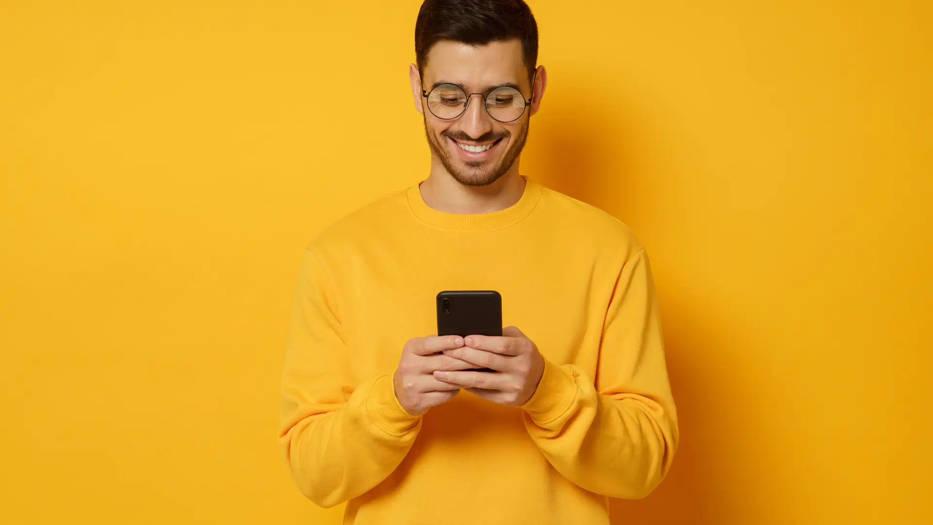 Joven con smartphone buscando como saber número de teléfono yoigo Joven con smartphone buscando como saber número de teléfono yoigo