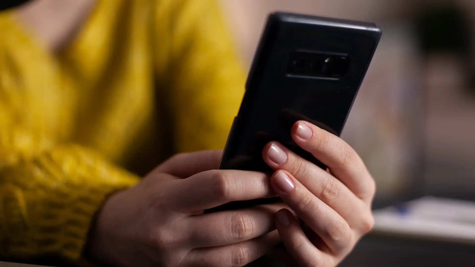 Una mujer sujetando su teléfono móvil mientras desbloquea la ESIm que tiene con la compañía Yoigo