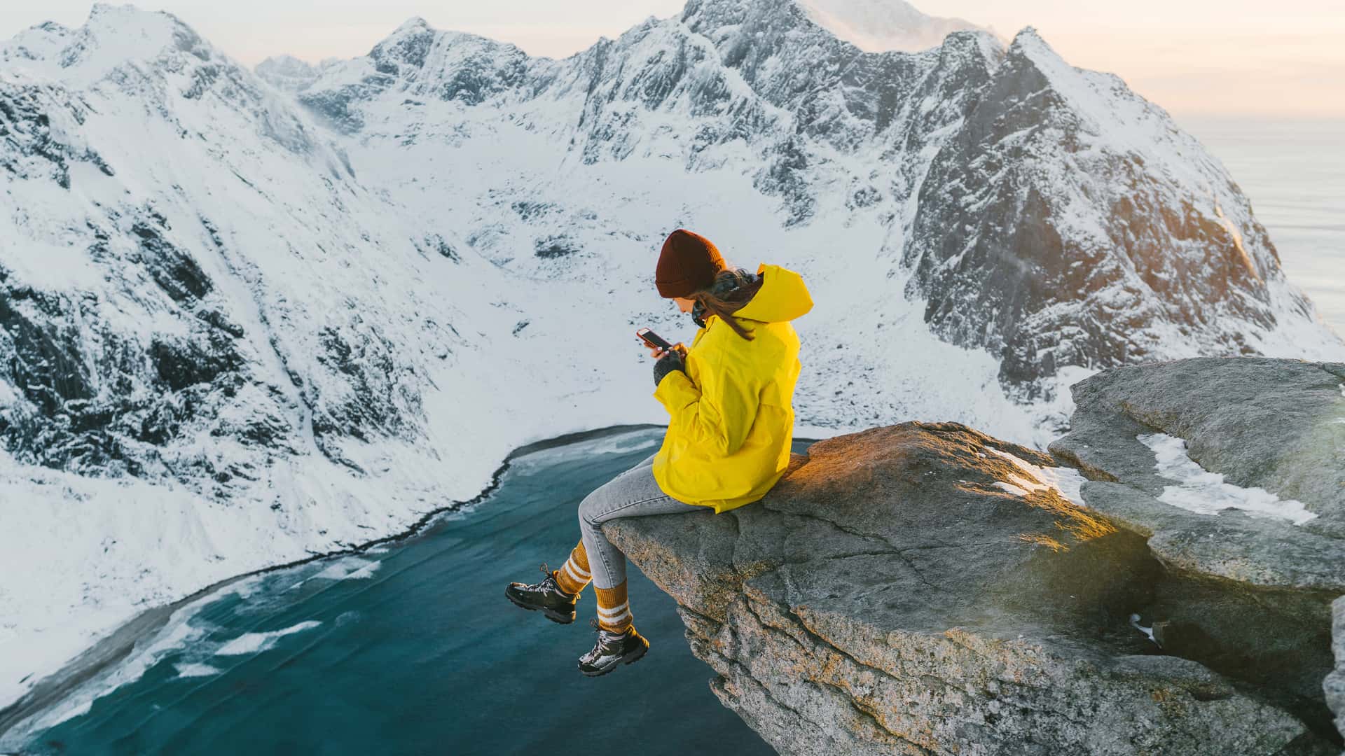 Mujer sentada en el acantilado y usando el teléfono inteligente representa itinerancia de datos de yoigo