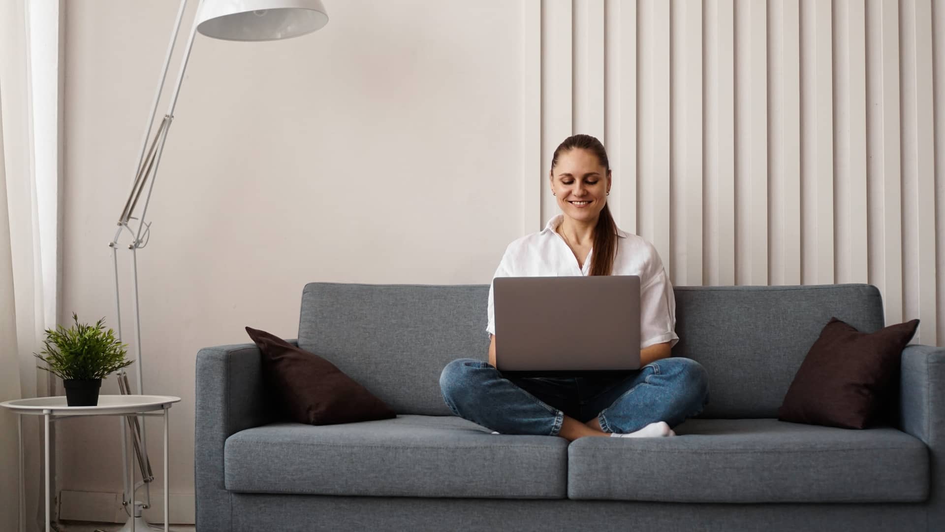 muejr disfrutando de su tarifa de internet mientras trabaja con su ordenador en el sofa de casa