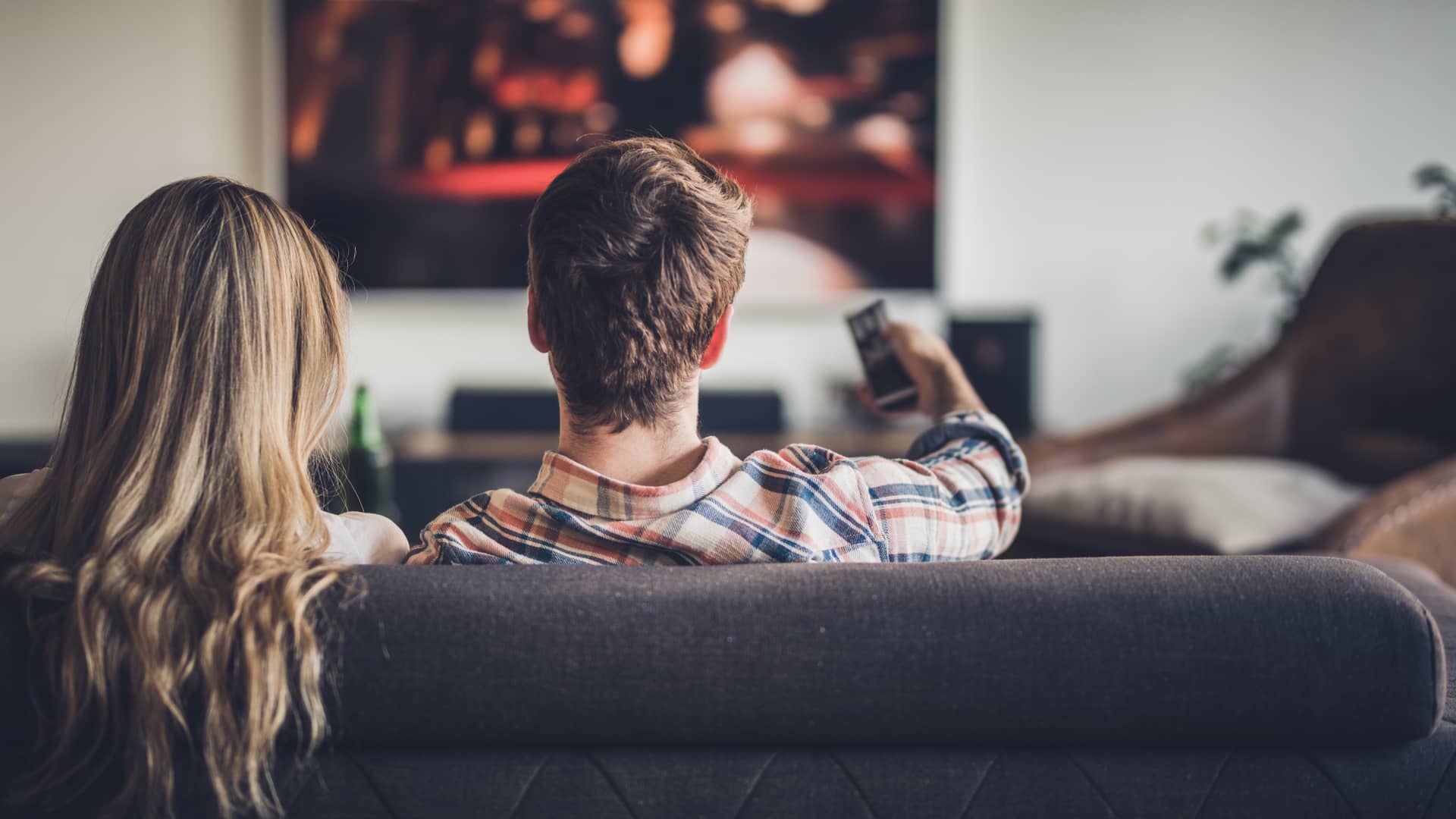 Una pareja viendo en su televisión canales premium desde su sofá gracias a su tarifa de TV
